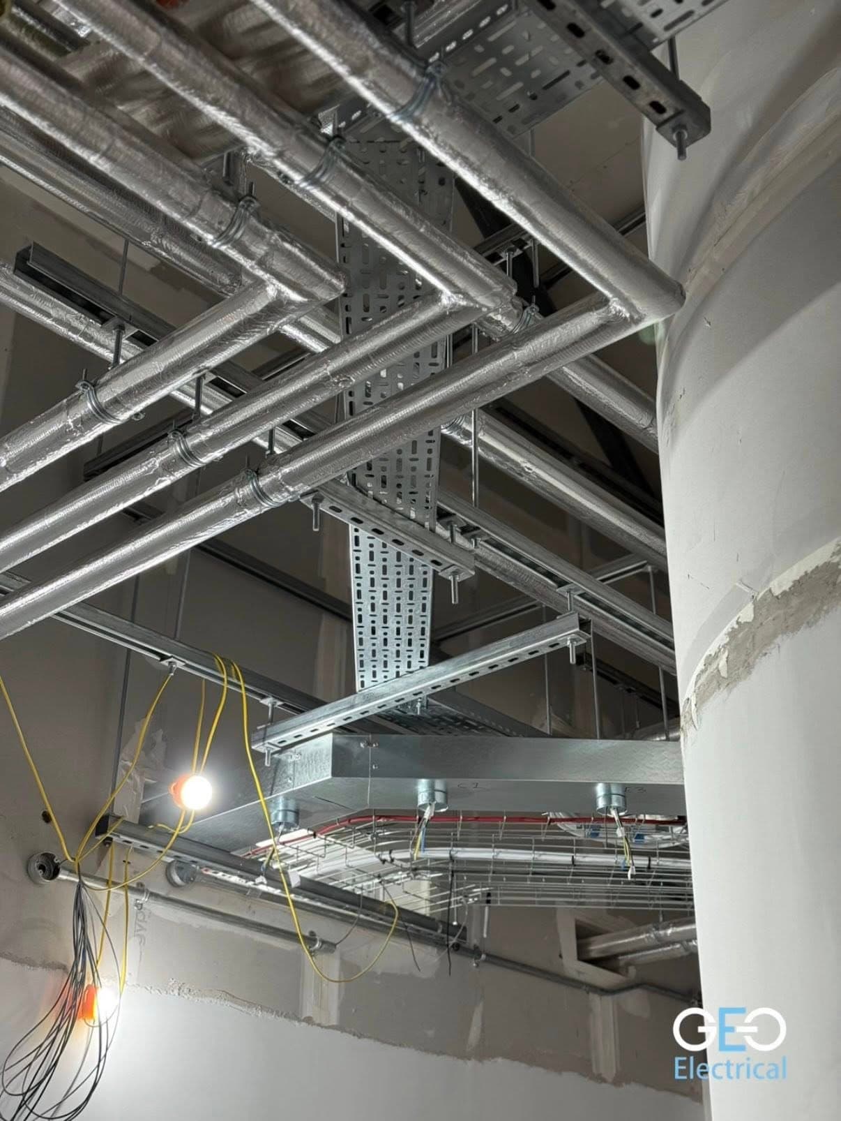 Galvanised cable tray and containment under a steel-framed industrial roof